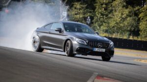 A gray Mercedes-AMG C63 slides in a cloud of smoke.